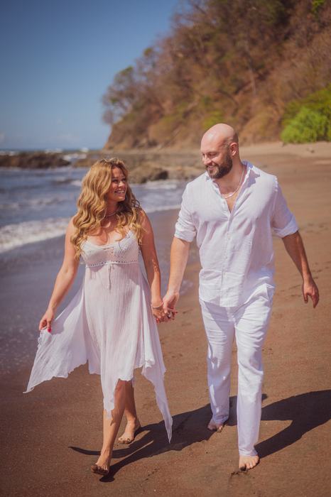 Pamela and Tanner walking hand in hand along the shore