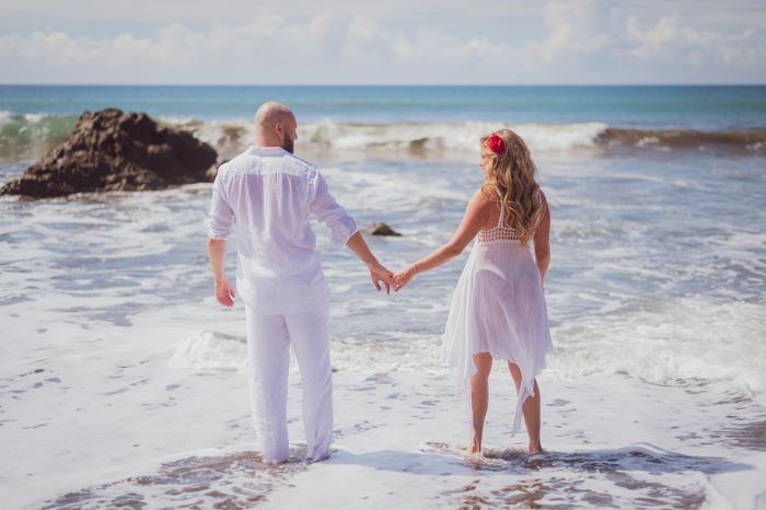 Pamela and Tanner walking into the surf, hands linked