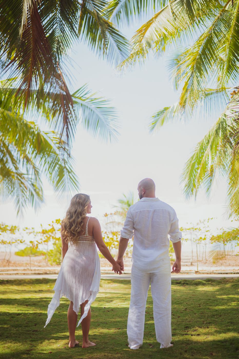 Pamela and Tanner beneath the palms, looking out to the water